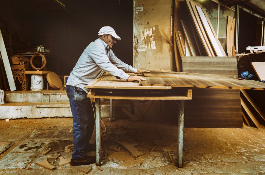 Pengrajin memotong papan kayu dengan mesin gergaji